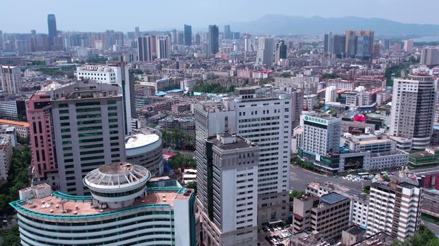 A daytime aerial view of a densely built urban area with various high-rise and mid-rise buildings forming a cityscape.