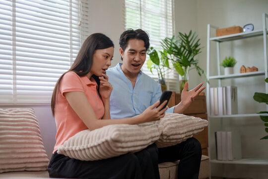 Asian couple feeling excited and surprised looking at smartphone
