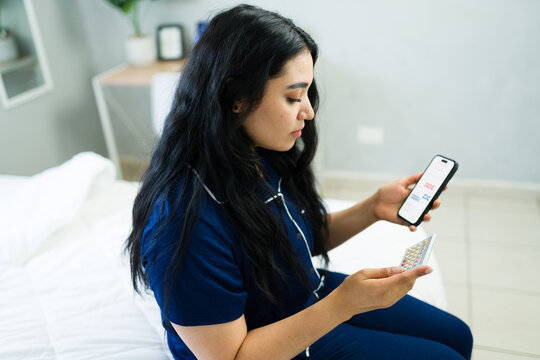Young woman managing contraception with birth control pills and smartphone app for daily reminder and tracking