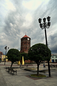 Historic gothic Town Hall Tower in Żnin with a tower clock against a dramatic, stormy sky over the market square