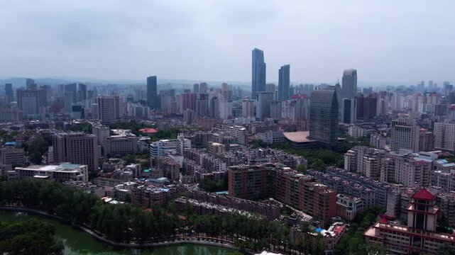 An aerial panorama of a sprawling modern urban area with mixed high-rise and mid-rise buildings under an overcast sky.