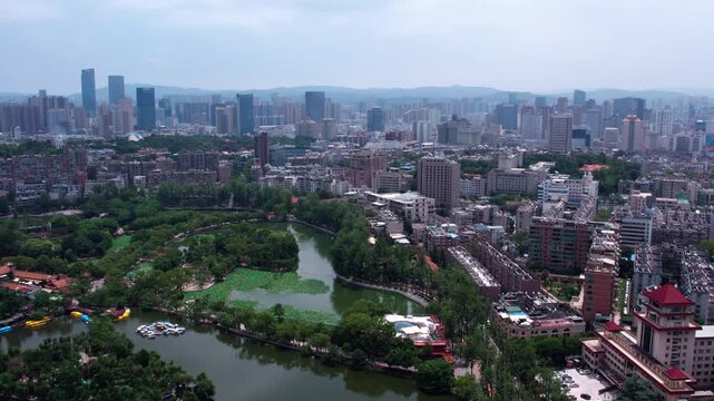 An aerial perspective shows a city combining natural parkland, water bodies, and modern urban architecture with distant hills.