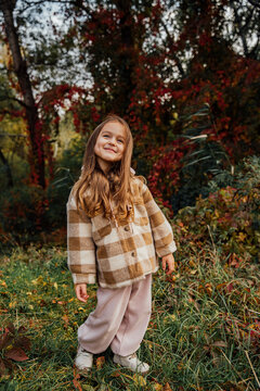 Young girl enjoying a playful autumn day outdoors surrounded by vibrant foliage.