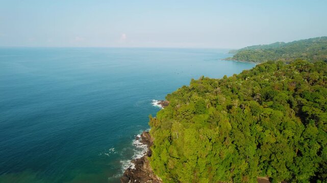 Green rainforest cliffs meeting Pacific Ocean near Playa Hermosa in Costa Rica