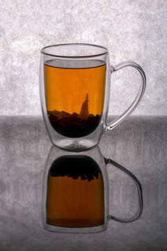 A glass of brewed tea on a gray background with a reflection