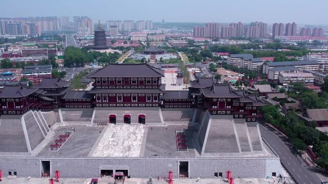 Aerial view of a grand traditional Chinese palace building set within a modern urban area, with adjacent historic structures.