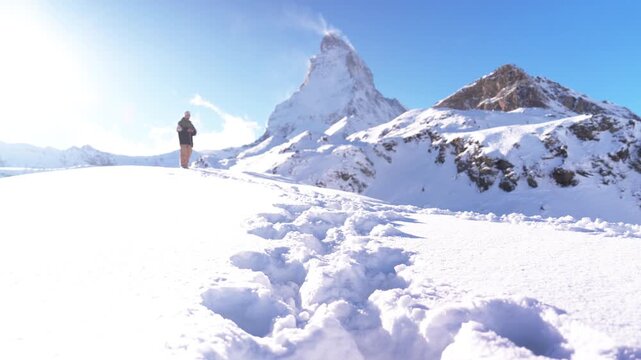スイス・マッターホルンを望む雪原を歩く登山者、ツェルマットの冬景色（Matterhorn Switzerland Snow Hiker）