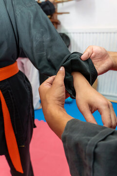 Two people are practicing a hapkido martial art technique with one person grabbing the other's wrist while wearing an orange belt