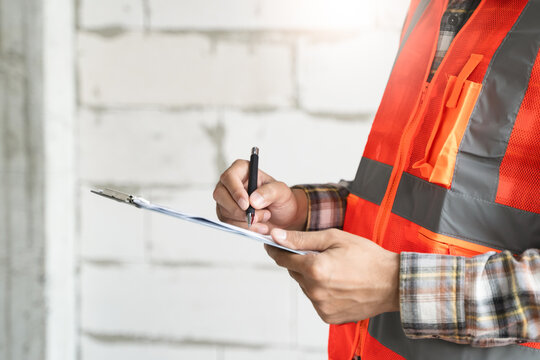 Asian inspector checking structure of new property and taking note in the clipboard for review and fix the house before sell to client