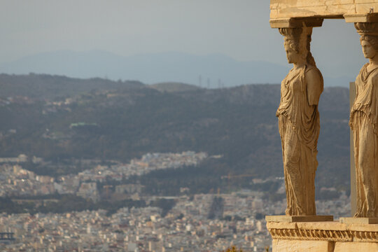 Close-up of two Caryatids statues of the Porch of the Maidens on the Erechtheion at the Acropolis, Athens, overlooking the distant city.
