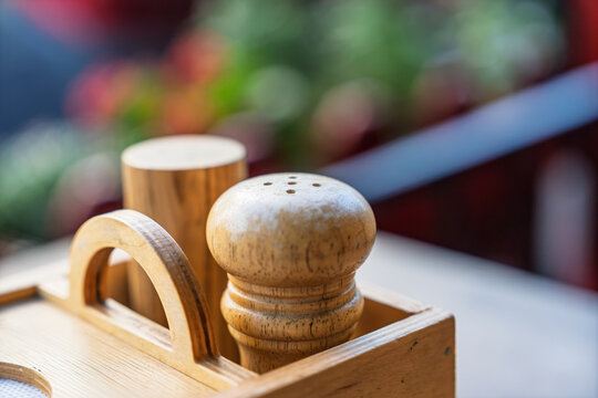 Wooden salt and pepper shakers in a rustic holder on a restaurant table