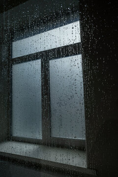Raindrops on a window pane during a gloomy overcast day