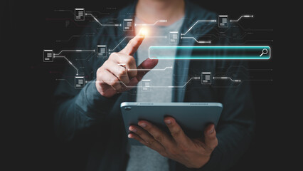Casual businessman using tablet with digital search bar and connected documents, representing online research, data management, information technology and smart digital solutions. © panya7