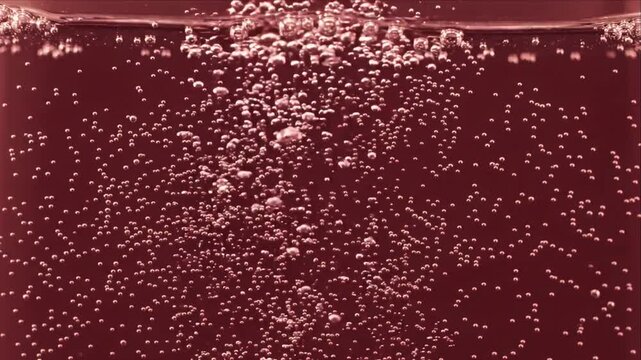 Abstract background featuring sparkling bubbles rising through crimson liquid underwater, rich red maroon water texture with dynamic effervescent motion, fluid carbonated pattern for beverage design