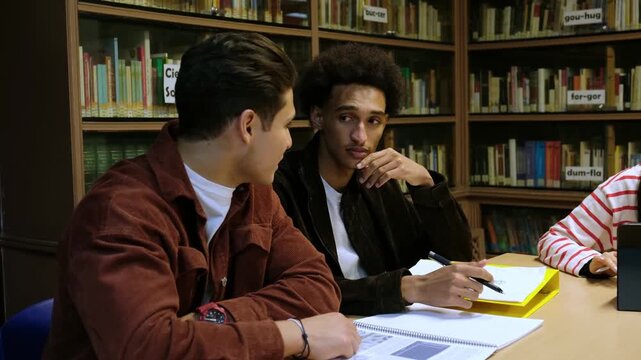 Young male university students collaborating on a project in a high school library