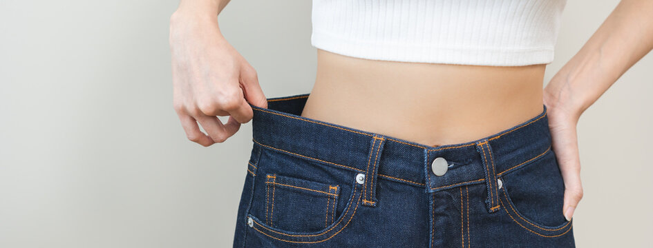 Shape slender, thin waist, slim fit asian young woman, showing body shape her weight loss, happy wearing in big, large or oversize jeans, excess lose by diet and exercise. Healthy lifestyle concept