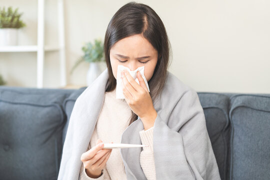 Sick, influenza asian young woman tired have a fever and sore cough hand holding thermometer for check measure body temperature, illness while rest at home. Health care with disease, pandemic virus.