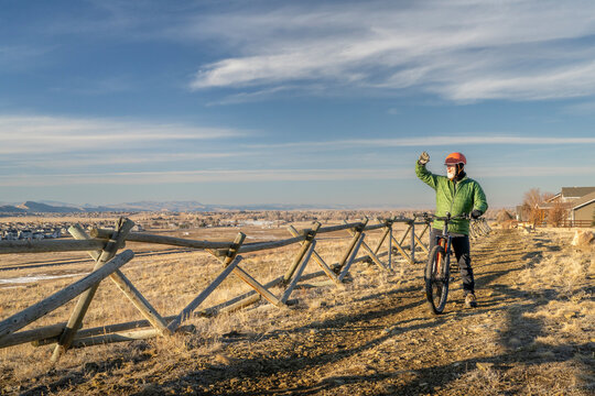 senior male cyclist with a mountain bike on a dirt trail overlooking Colorado foothills