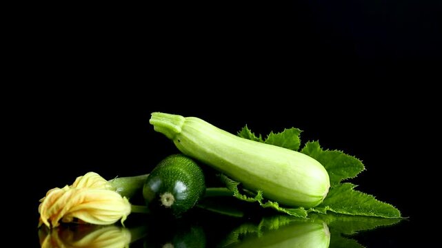 Light green zucchini with yellow flower on black reflective studio background