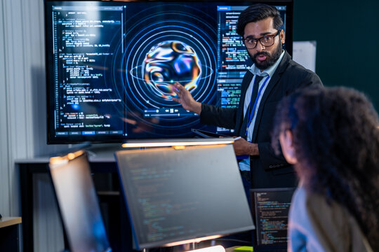 Software engineer documenting technical specifications and programming logic on a tablet while reviewing AI code deployment with a team colleague.