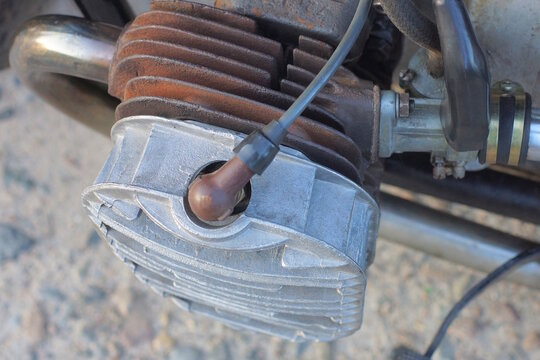 part of one old motorcycle with gray iron radiator and carburetor on summer street