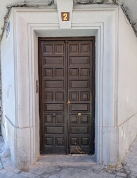Fachada de la esquina de un edificio antiguo con puerta doble de madera oscura, robusta y con un dise&ntilde;o cl&aacute;sico, con pomos redondos met&aacute;licos. Madrid, Espa&ntilde;a 
