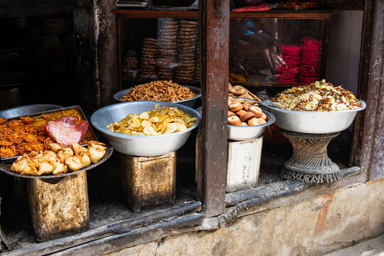 Four large bowls of street food in a poor section of Varanasi India on a porch stoop.