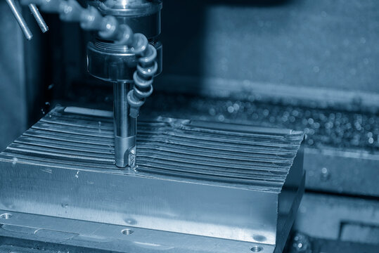 Rough cutting process on steel mold parts using indexable milling tool on CNC machine in light blue tone