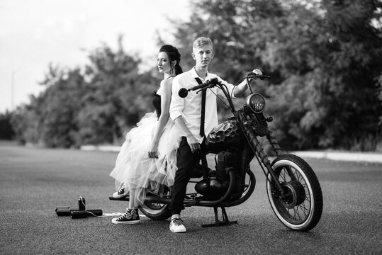 A couple of newlywed freaks on a black custom bike