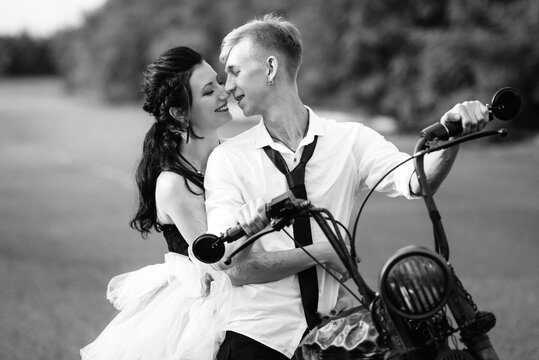 A couple of newlywed freaks on a black custom bike