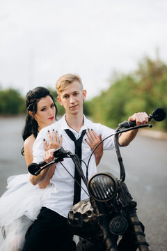 A couple of newlywed freaks on a black custom bike