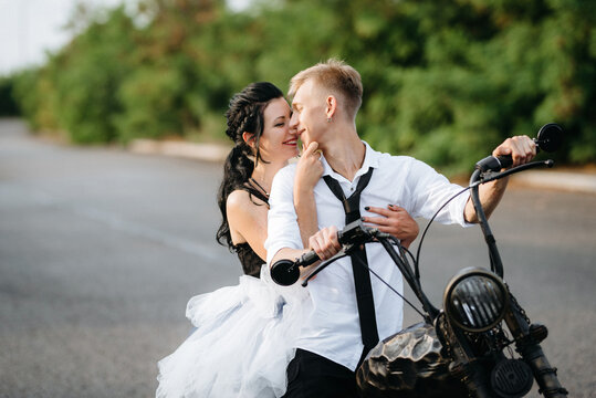 A couple of newlywed freaks on a black custom bike