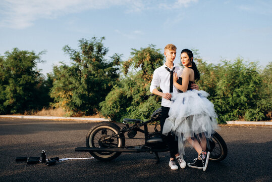 A couple of newlywed freaks on a black custom bike