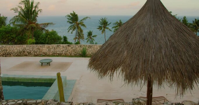 Thatch umbrella shades pool deck with ocean view at luxury resort in Nusa Penida