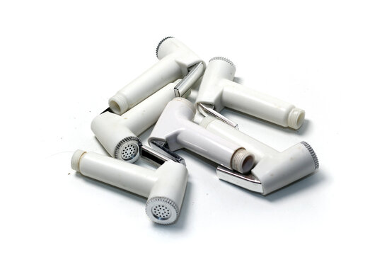 A pile of white plastic bidet sprayer heads isolated on a solid white background.