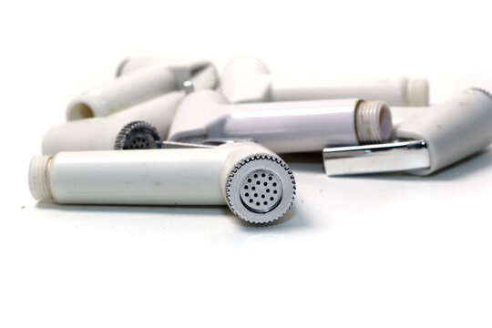 A low-angle close-up shot of several white plastic bidet sprayer nozzles stacked together on a white background.