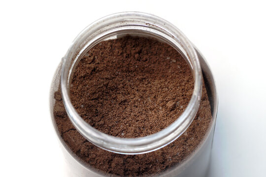 close-up view of dark brown ground coffee powder inside an open plastic container.
