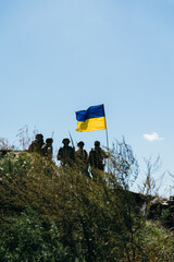 Naklejka premium Ukrainian soldiers standing with national flag in field