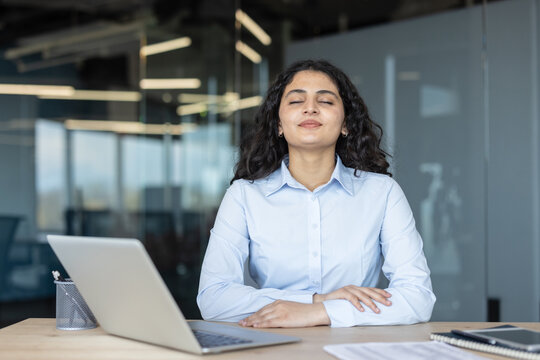 Businesswoman relaxing with closed eyes at an office desk, finding peace and balance during a work break, practicing mindfulness for stress relief and mental well-being