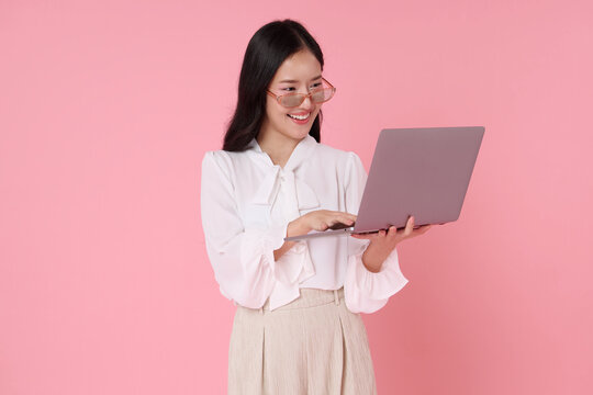 Asian businesswoman using laptop and smiling representing digital productivity remote work online communication career success confidence technology and modern professional lifestyle.