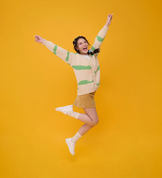 Young Asian woman jumping with raised arms expressing joyful celebration freedom positive energy personal success confidence youthful optimism achievement and carefree lifestyle.