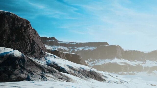 Mountains stand tall with snow covering their bases under a sunny blue sky. The bright daylight shows the rocky textures of the peaks and the smooth snow below.
