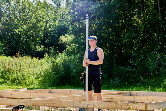Surveyor grips graduated measuring rod firmly while checking position for accurate land measurements and construction site planning.