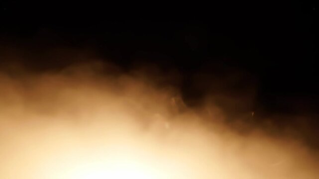 Abstract golden smoke or fog effect slowly rising from the bottom against a dark background, creating a mysterious and atmospheric visual for various projects.