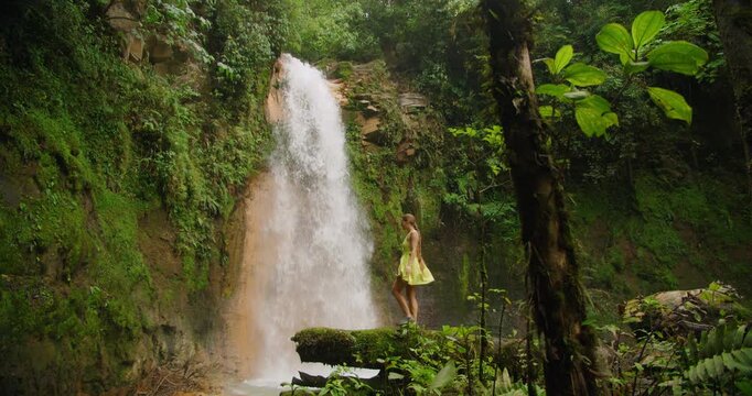 Woman walking in the jungle viewing the powerful Blue Falls waterfall in Costa Rica