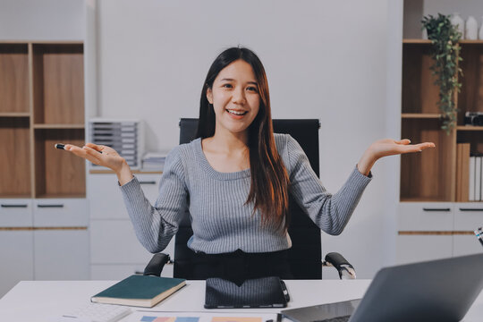 young woman is working on laptop in modern office environment, showcasing focused and productive atmosphere. She is dressed in professional white shirt, with coffee cup and small plant on table,
