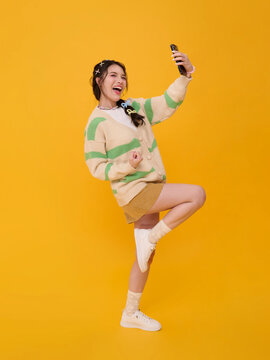 Young Asian woman taking smartphone selfie while celebrating expressing social media lifestyle confidence happiness digital connection personal branding and youthful online engagement.