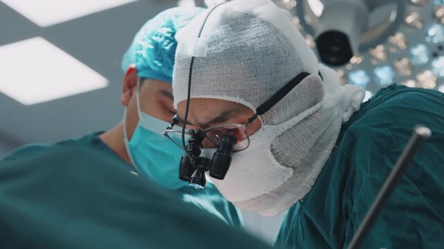 Close-up of a focused surgeon wearing magnifying loupes while performing a precise surgical procedure in the operating room