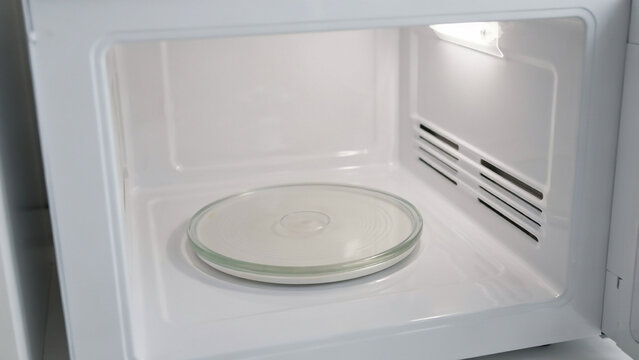 Empty white microwave oven interior with glass turntable plate