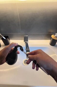 Person squeezing toothpaste on brush in evening bathroom